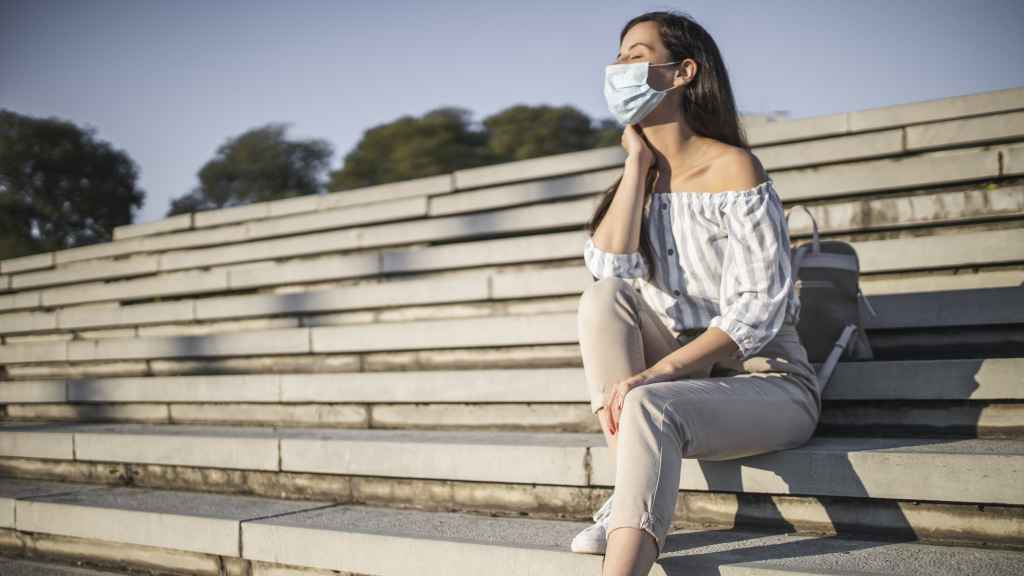 Una mujer toma el sol con mascarilla.