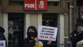 Una profesional del sector de la peluquería y estética se concentra con una pancarta que pide la bajada del IVA al 10% frente a la sede del PSOE, en Madrid (España). Foto: Jesús Hellín - Europa Press