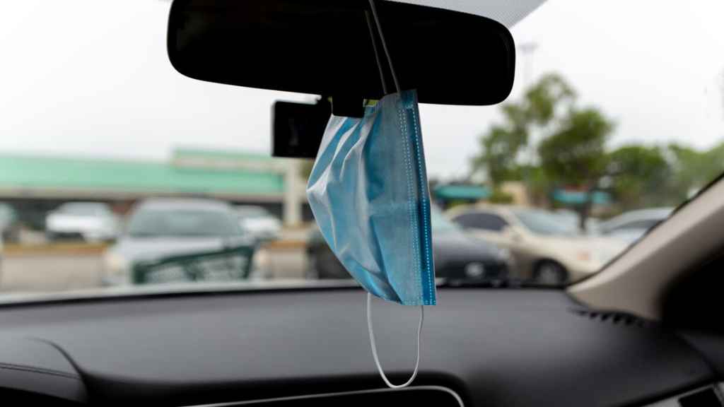 Una mascarilla colgada en el retrovisor de un coche.