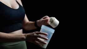 Una mujer echa proteínas en polvo en un shaker.