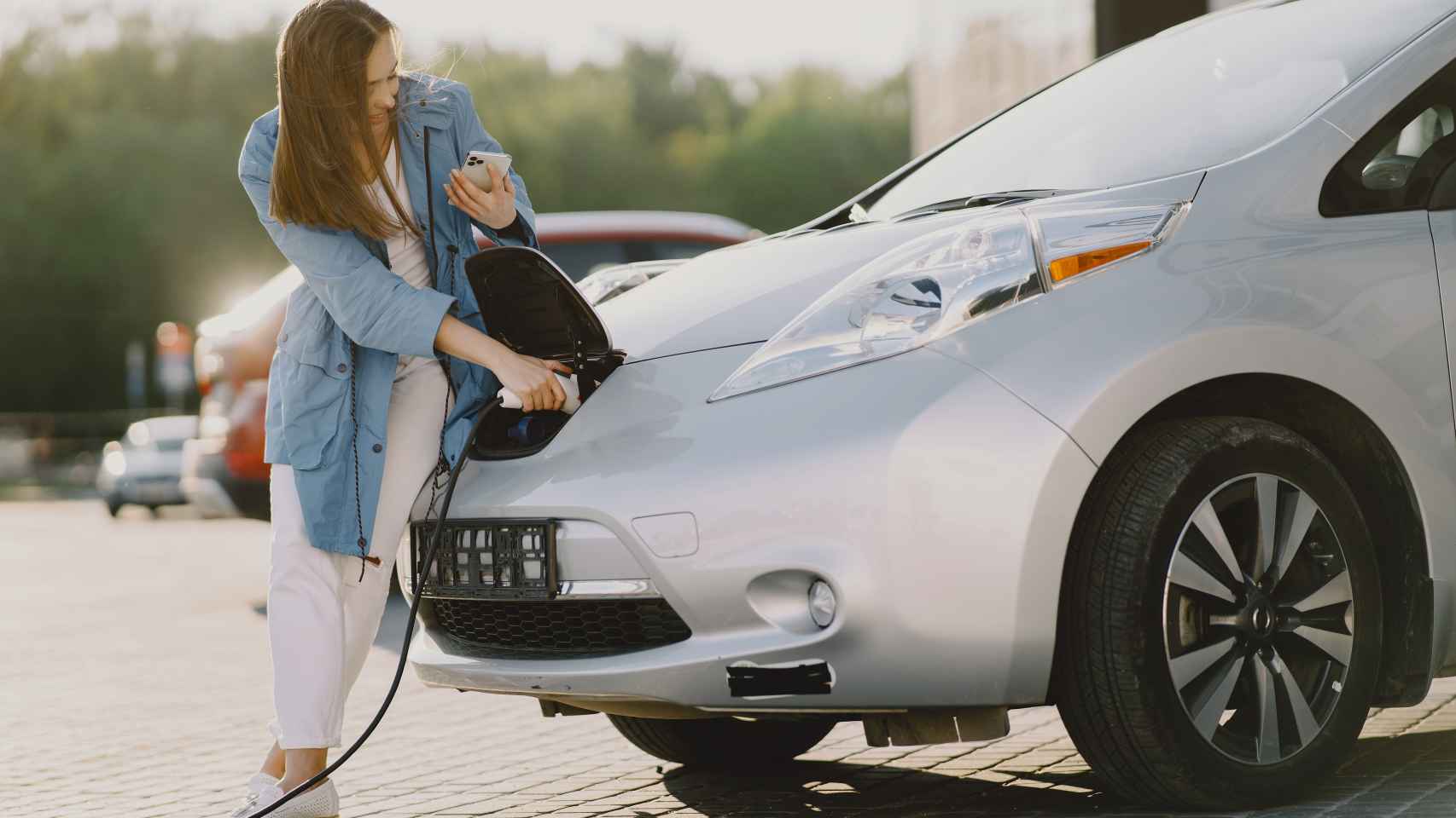 Una mujer cargando un coche eléctrico.
