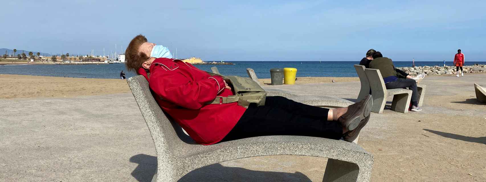 Una mujer descansa con una mascarilla en una playa de Barcelona.