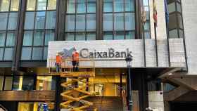 Unos operarios colocan el rótulo de CaixaBank en la antigua sede valenciana de Bankia.
