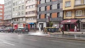 Los bomberos limpian la pintura vertida sobre la calzada en la Ronda do Outeiro.