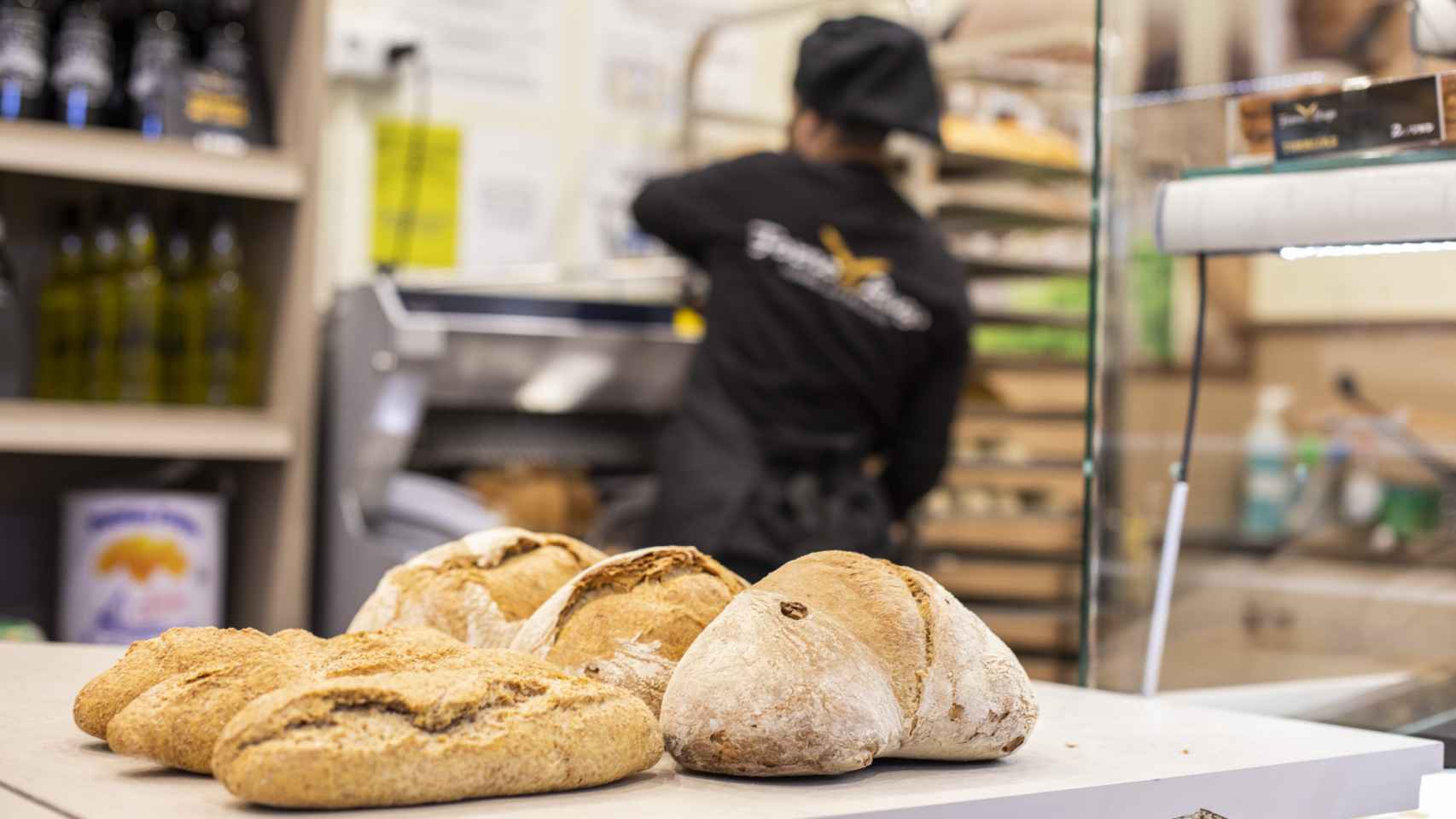 Los panes artesanales gallegos del Forno de Lugo y, de fondo, una trabajadora de la tienda.
