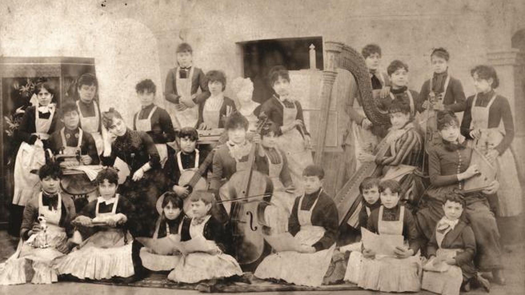 Clotilde Cerdà, con la cabeza apoyada sobre su mano, rodeada de las alumnas de la Academia de Ciencias, Artes y Oficios para la Mujer que fundó en 1885.