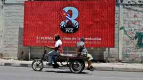 Dos personas pasan frente a una valla que promociona el VIII Congreso del Partido Comunista de Cuba.