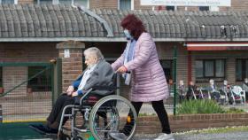Una mujer pasea a una anciana en silla de ruedas, en las inmediaciones de la residencia geriátrica de As Gándaras (Lugo).