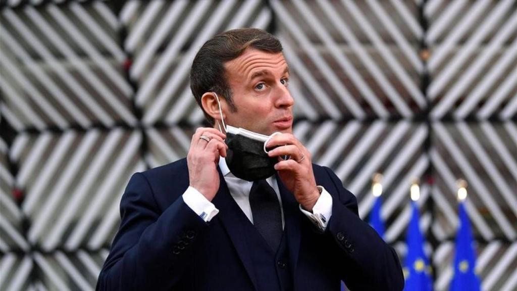 El presidente de Francia, Emmanuel Macron, se quita una mascarilla.
