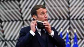 El presidente de Francia, Emmanuel Macron, se quita una mascarilla.