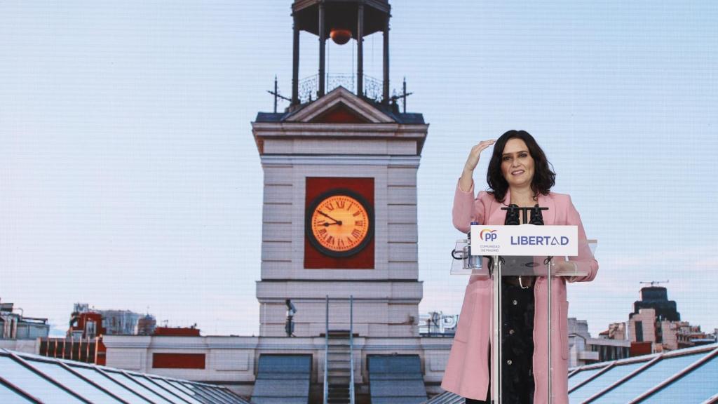 Ayuso, durante su intervención con una foto detrás de la Puerta del Sol.