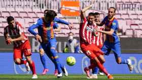Carrasco (Atlético) intentando llevarse un balón ante Piqué y Mingueza (Barça)
