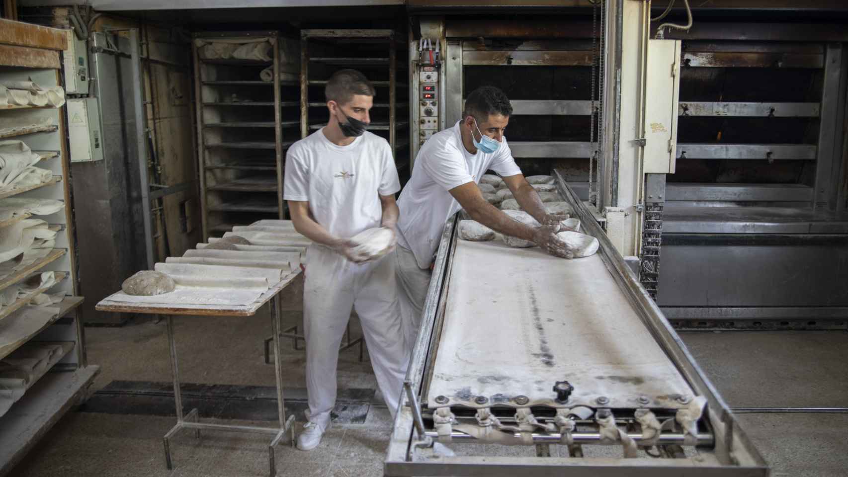 Dos trabajadores del obrador de Forno de Lugo, metiendo al horno el pan artesanal gallego recién amasado.
