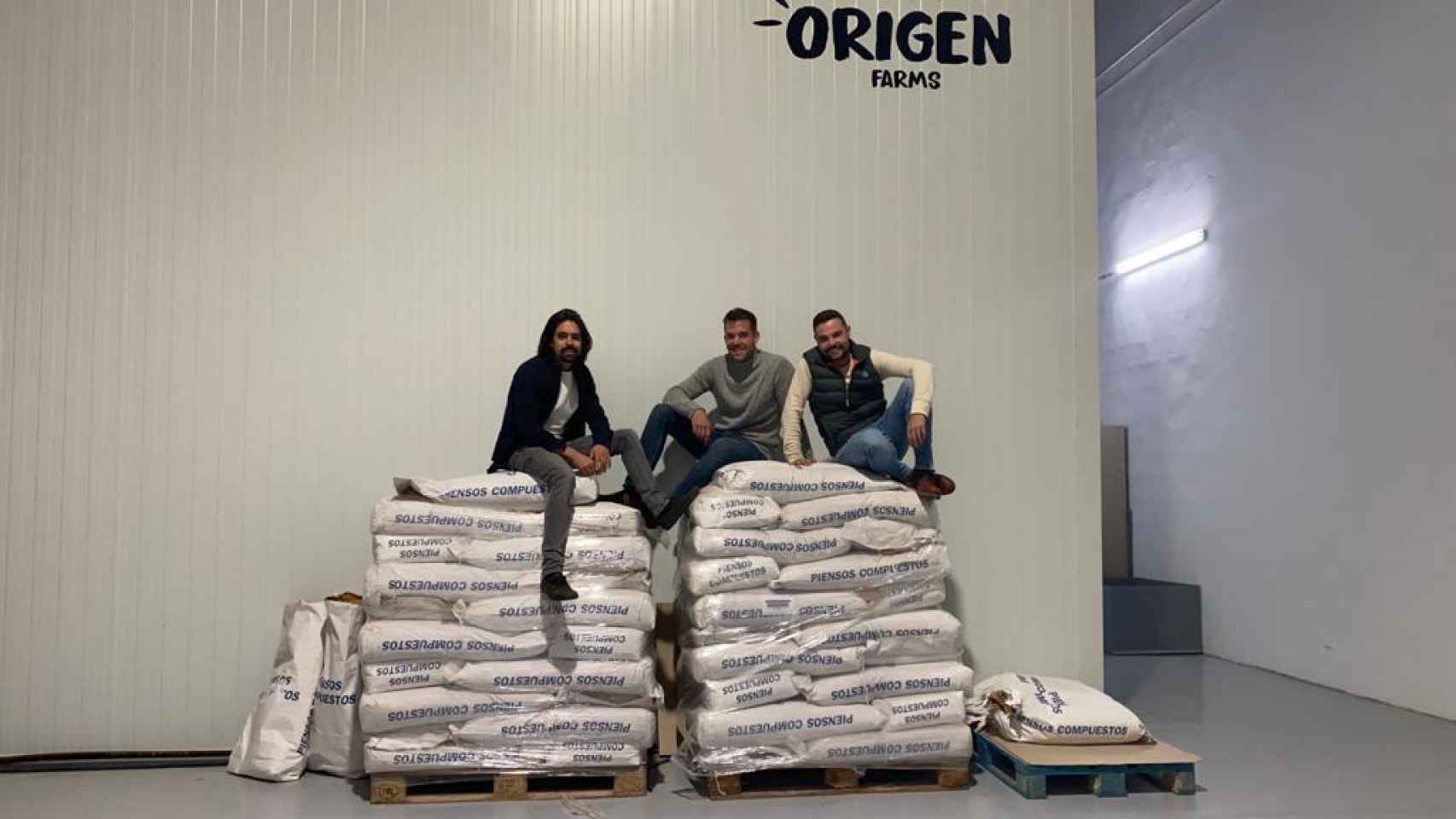 Los tres empresarios sobre los sacos de grillos de Origen Farms.
