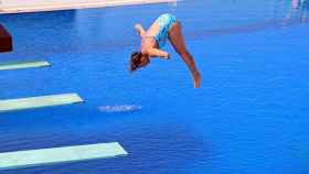 Una chica se lanza a una piscina desde un trampolín.
