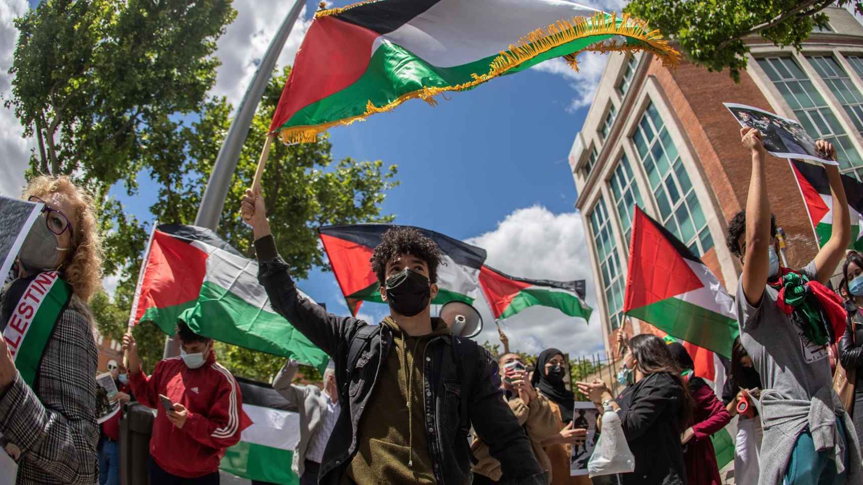 Varias personas ondean banderas del pueblo palestino frente a la Embajada de Israel en Madrid.
