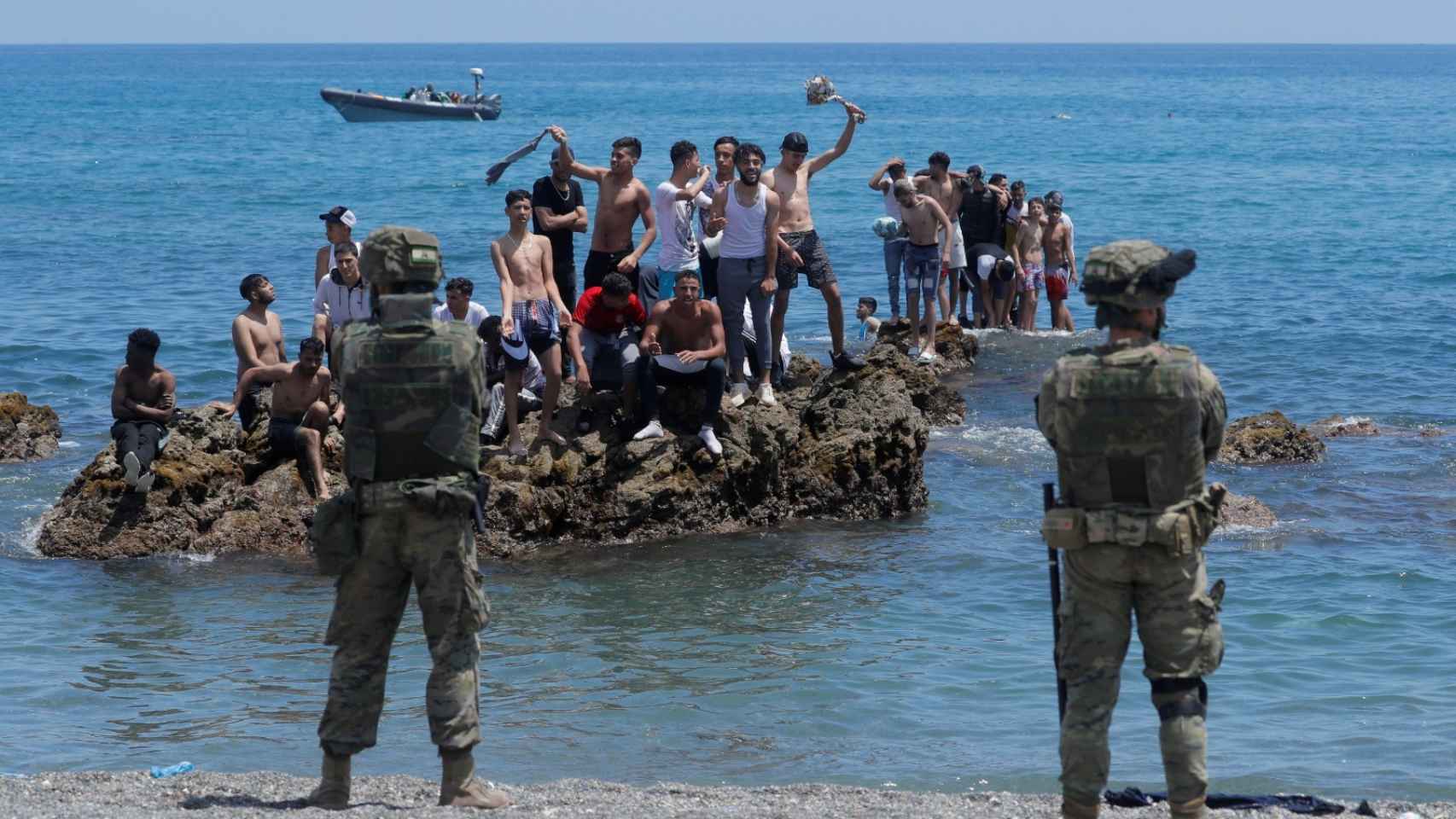 Un grupo de inmigrantes marroquíes, ante los militares españoles que patrullan la frontera de Ceuta.