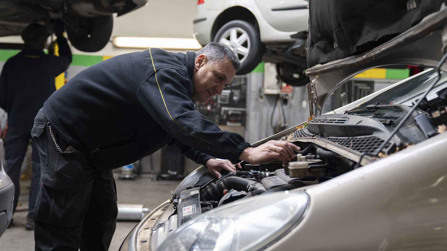 El mecánico José María Illán repara un vehículo en su taller en la 'preITV'.
