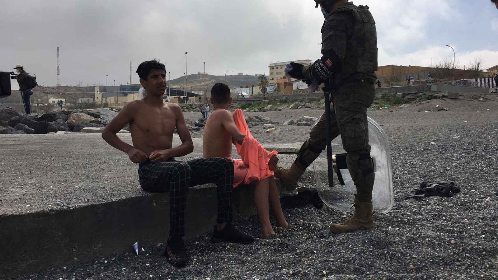 Un militar habla con dos menores después de sacarlos del agua en la playa de El Tarajal.