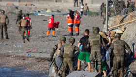 Miembros del Ejército ayudan a varios inmigrantes a su llegada a la playa de El Tarajal.