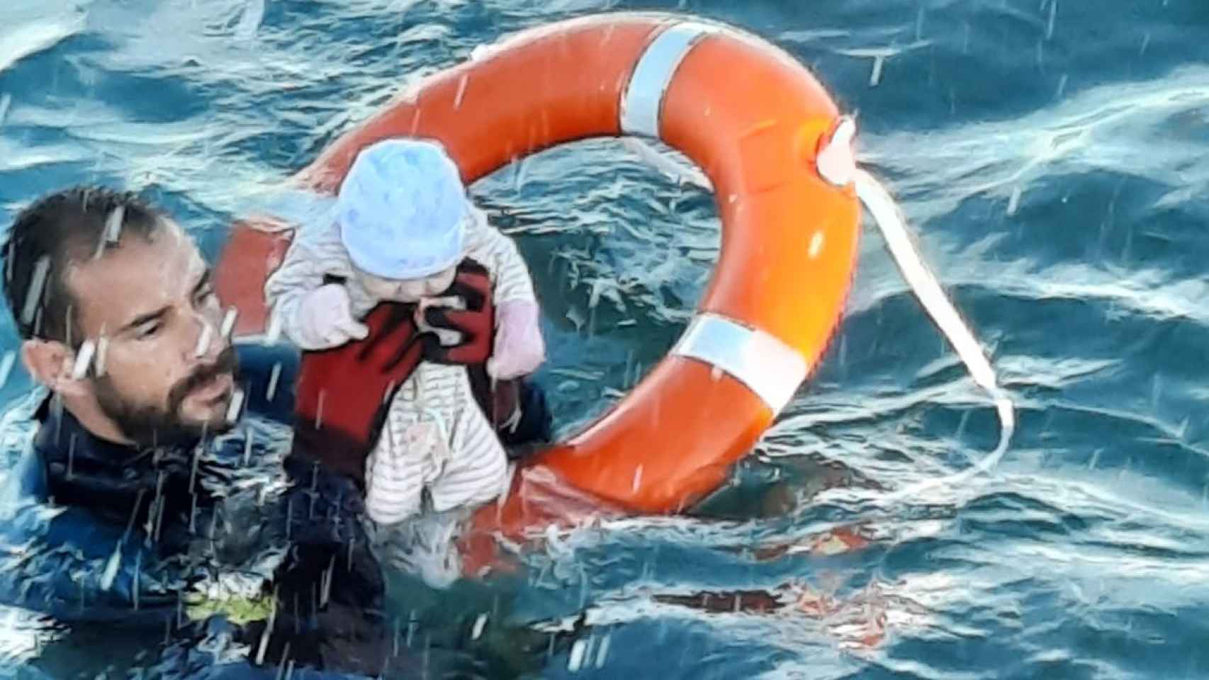 Un agente de la Guardia Civil sostiene a un bebé de pocos meses al que ha salvado en el agua de Ceuta. G