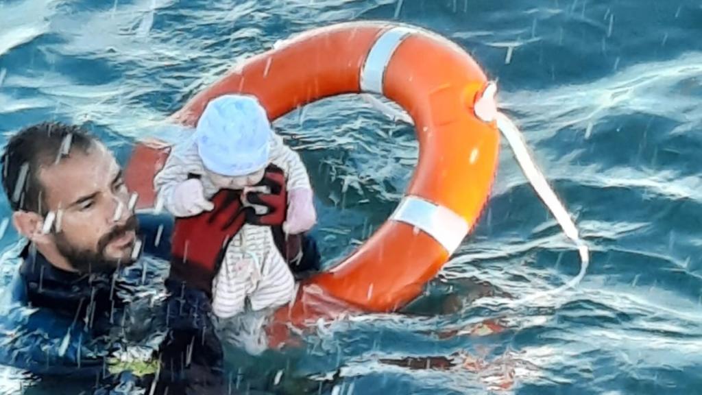Un agente de la Guardia Civil sostiene a un bebé de pocos meses al que ha salvado en el agua de Ceuta. G