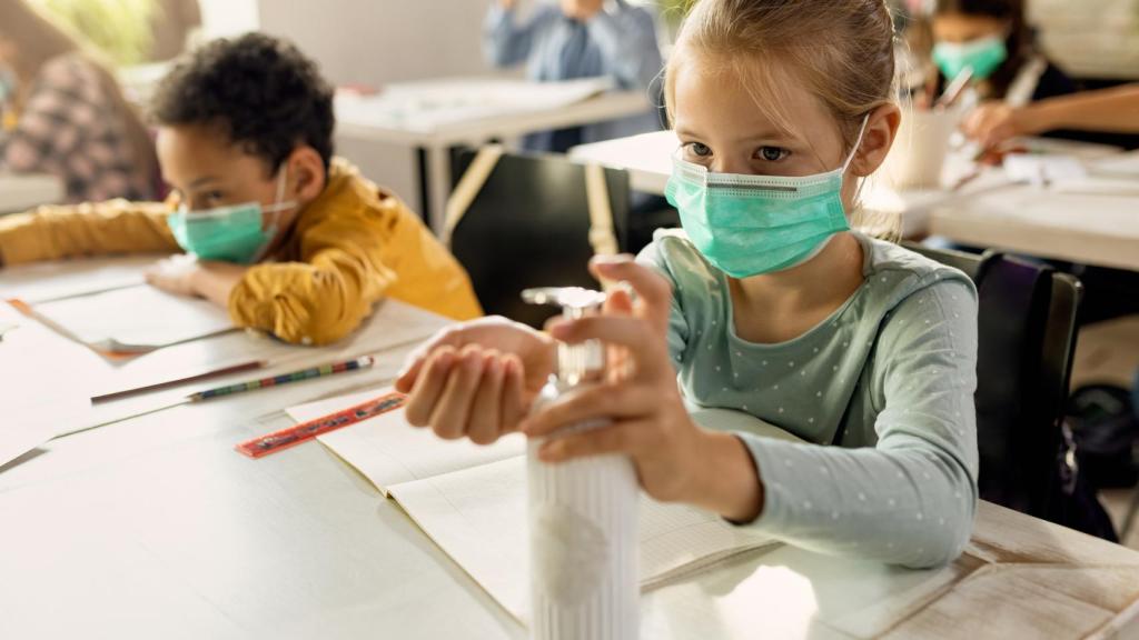 Dos alumnos utilizan mascarillas y gel hidroalcohólico en el aula.