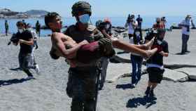 Un militar traslada en brazos a un menor llegado a las costas de Ceuta a nado.