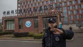 Un policía intenta evitar fotografías del Instituto de Virología de Wuhan durante la visita de la comitiva de la OMS.
