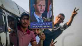 Un hombre con una pancarta de Bashar Al-Assad.