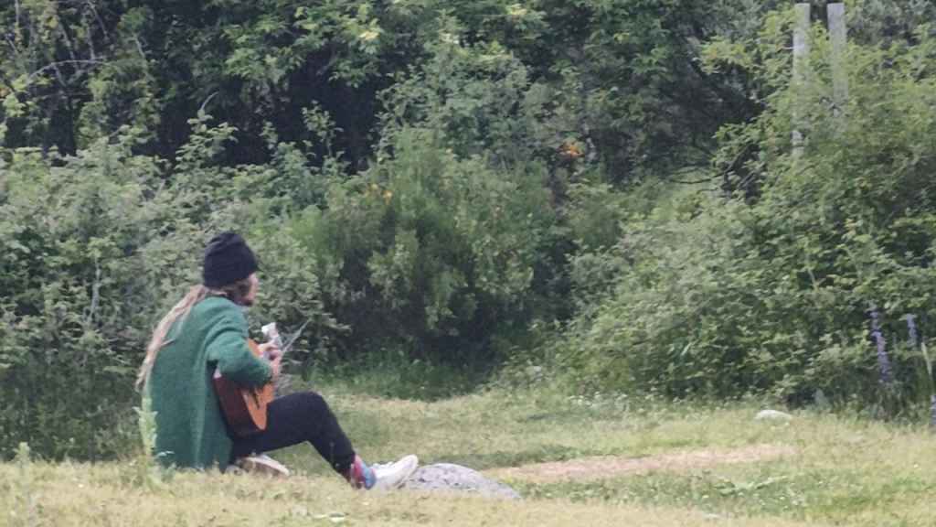 Un hermano de la Familia Arcoíris toca la guitarra en el campamento.