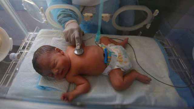 Un recién nacido siendo auscultado en la incubadora.