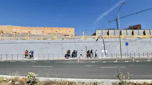 Varios migrantes procedentes de Marruecos hacen cola en las puertas de la frontera de Ceuta.
