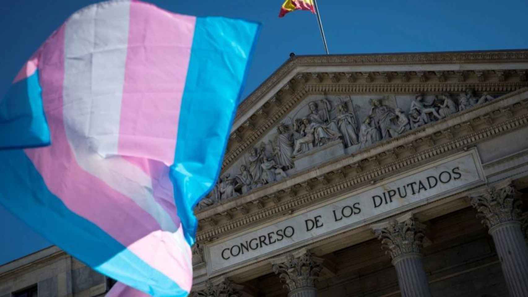 Una bandera del colectivo trans ondea frente al Congreso de los Diputados.