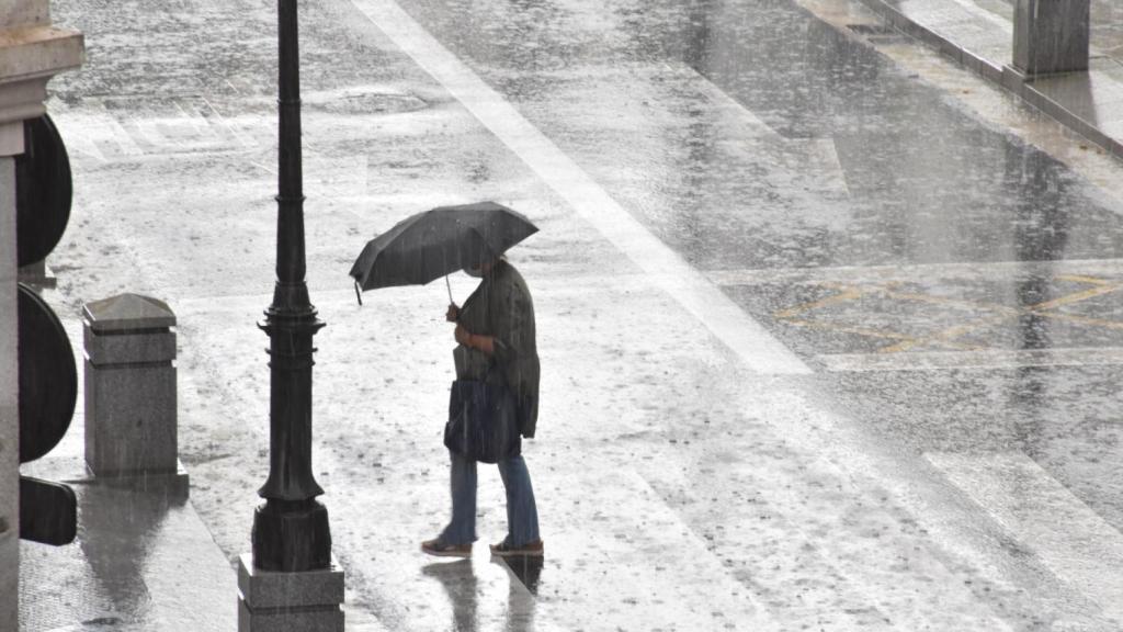 Una mujer se protege de la intensa lluvia con su paraguas