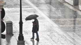 Una mujer se protege de la intensa lluvia con su paraguas