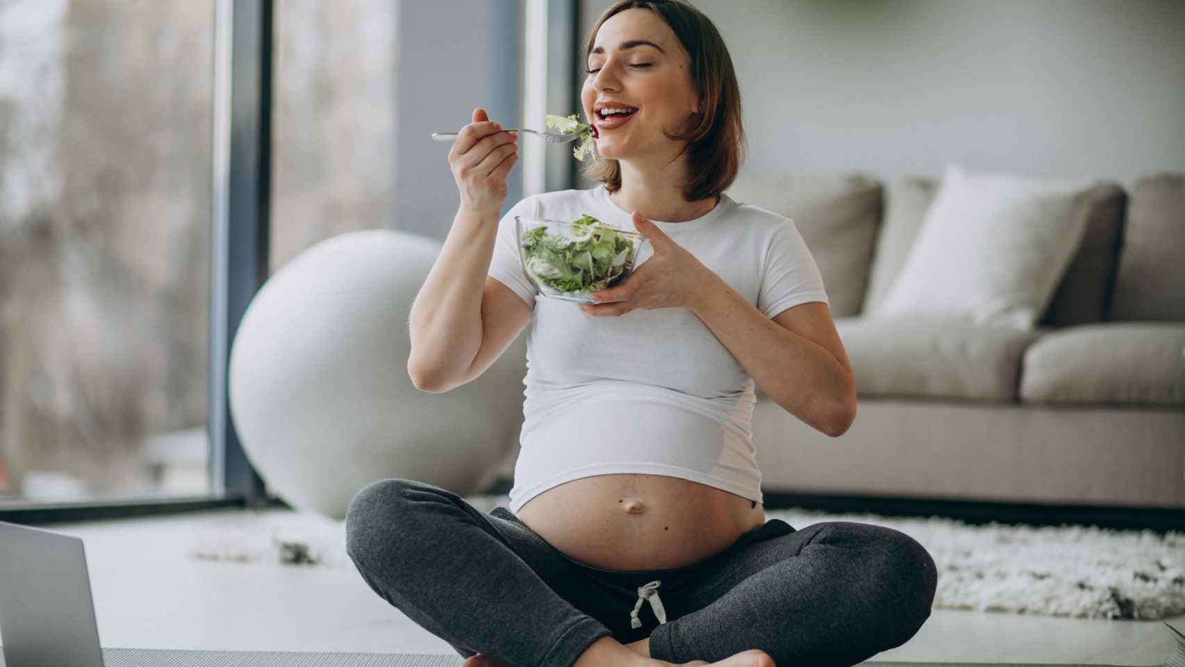 Una embarazada toma una ensalada.