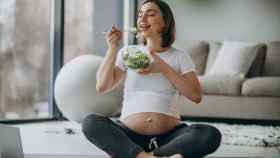 Una embarazada toma una ensalada.