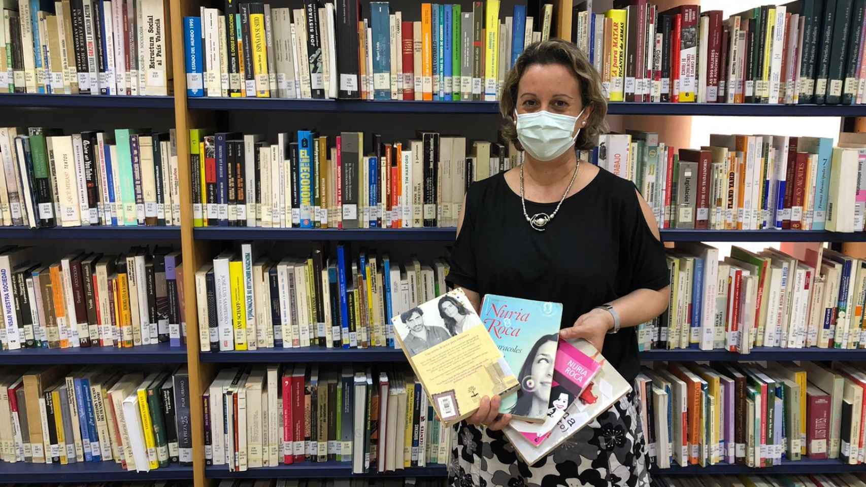 Marta, bibliotecaria de Moncada, posa con los libros de Nuria Roca. EE