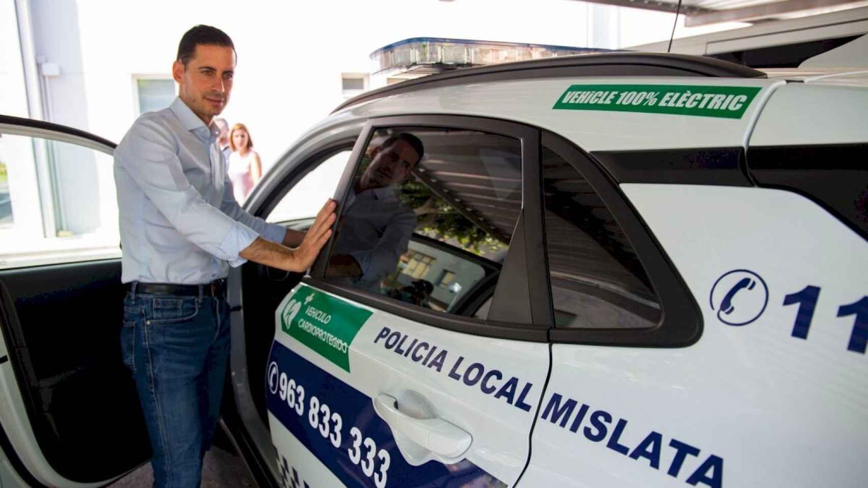 El alcalde de Mislata, Carlos Fernández, junto a un coche de la Policía Local. EE