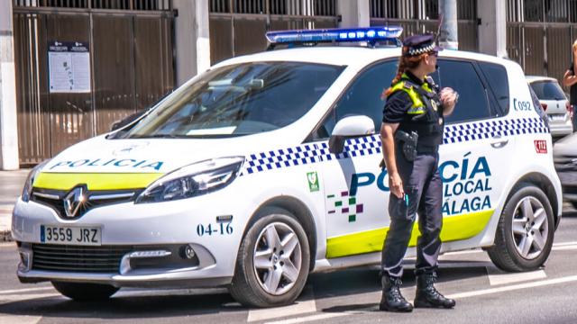 Una agente de la Policía Local de Málaga junto a un coche patrulla.