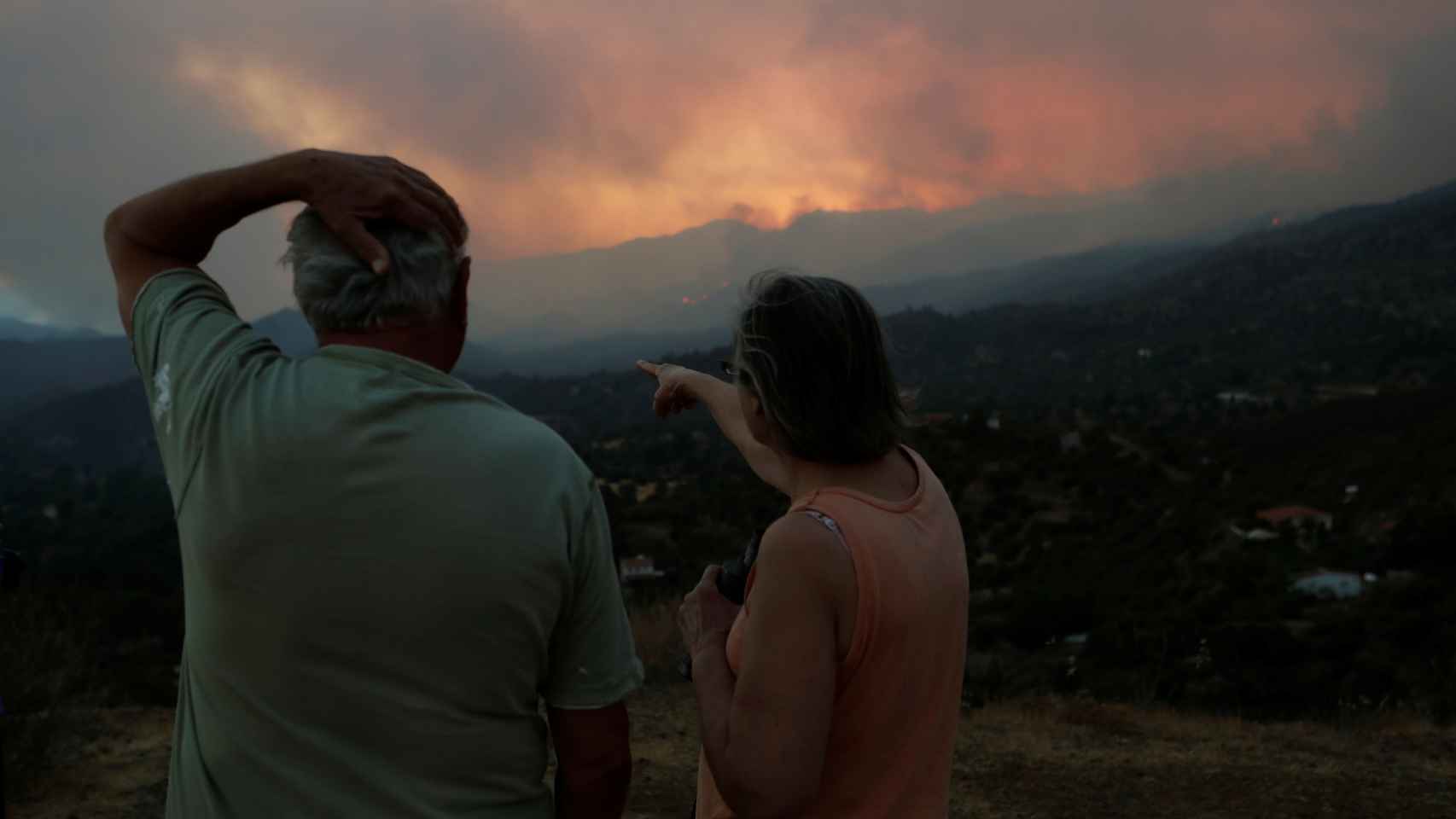 Dos personas en el distrito de Lárnaca contemplan el incendio que ha arrasado Chipre.
