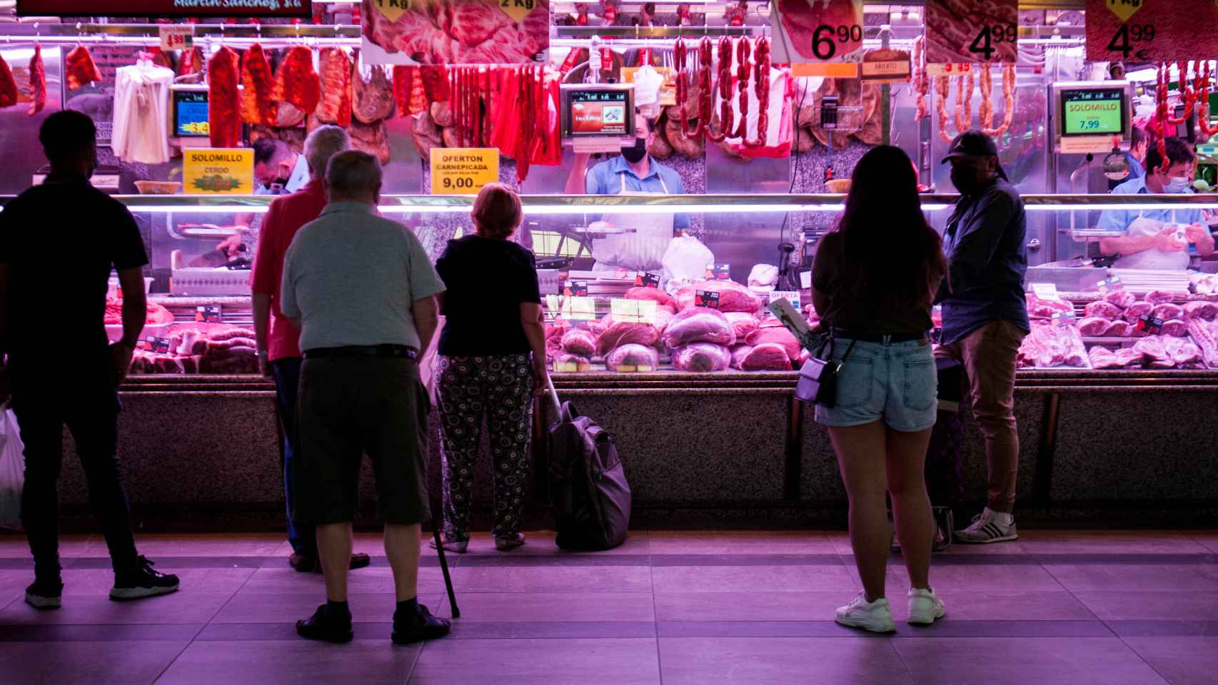Varias personas hacen cola en una carnicería del Mercado de las Maravillas de Madrid.