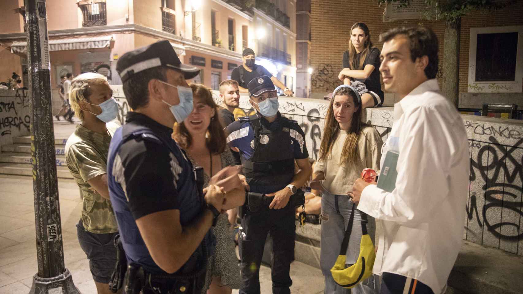 Agentes de la policía municipal hablan con un grupo de gente en la plaza del Dos de Mayo.