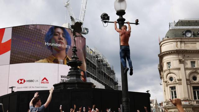 Un aficionado inglés se encarama a una farola en Piccadilly Circus en la previa del Italia - Inglaterra