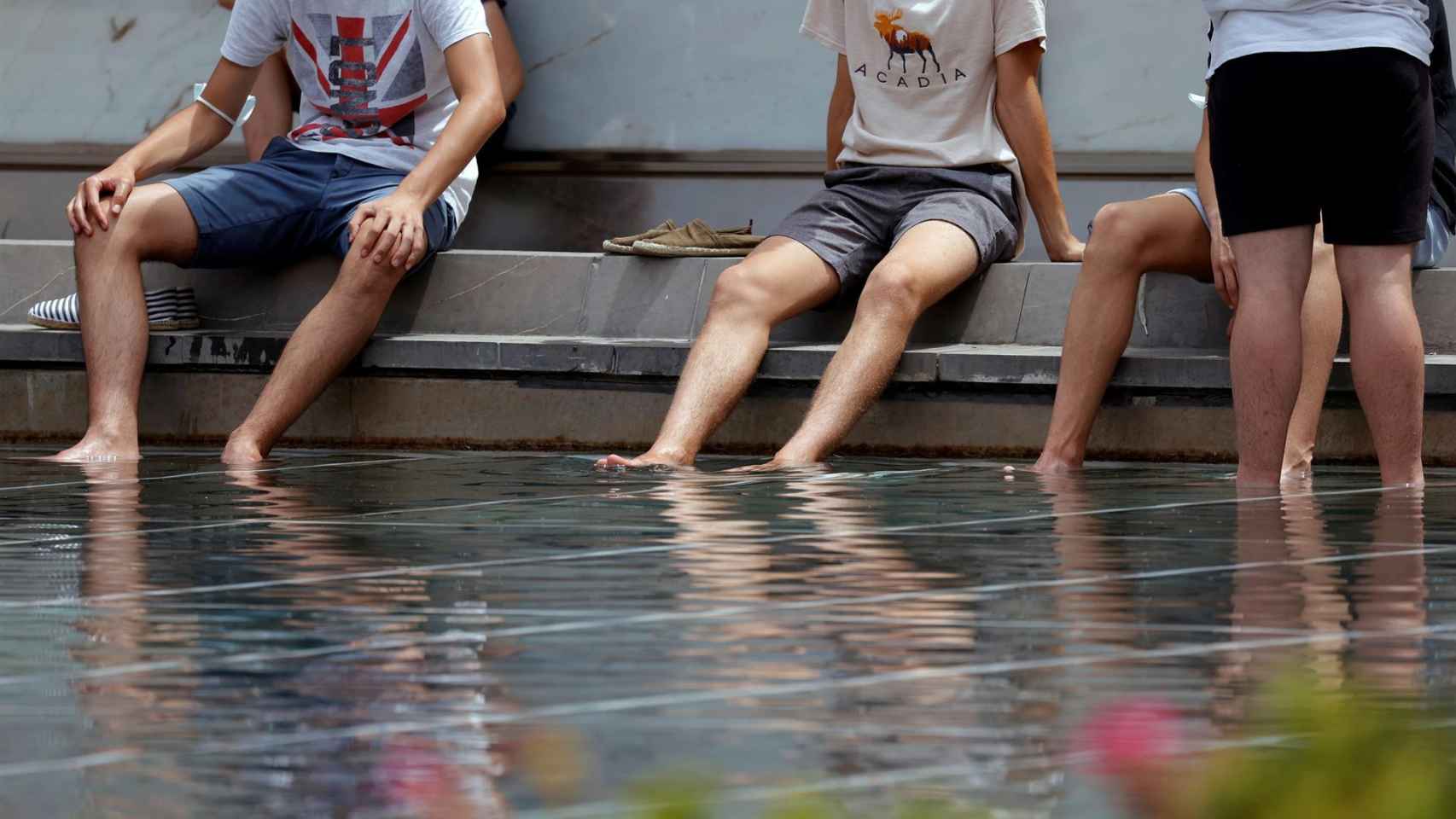 En la foto, un grupo de jóvenes se refrescan en un estanque de Valencia.