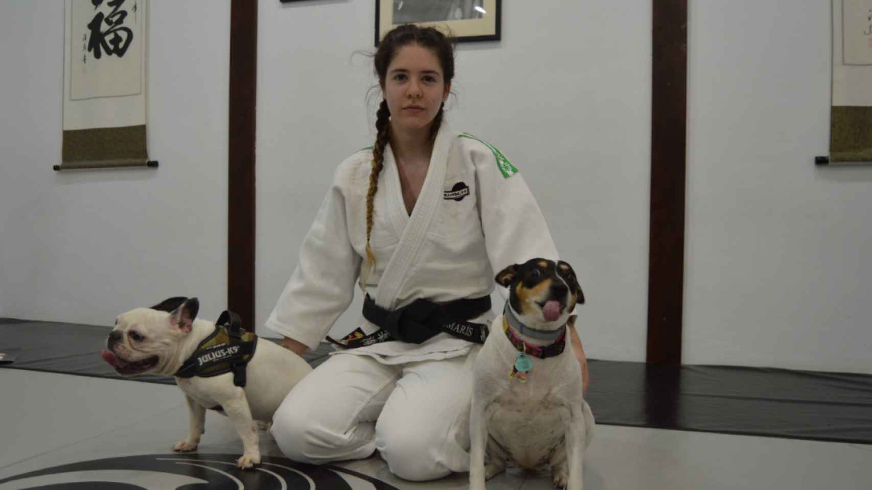 Sandra L. Romarís posando con sus dos perritas en el dojo donde entrena.