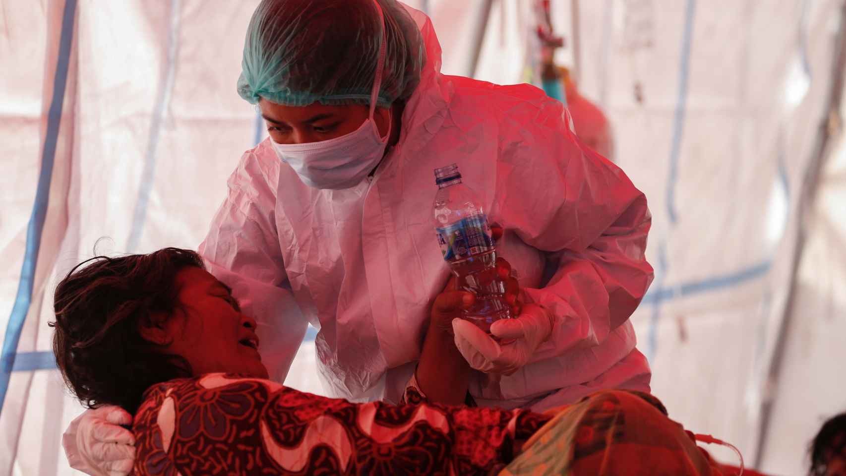 Un sanitario equipado con un un EPI atiende a un paciente de Covid en Bekasi (Indonesia).