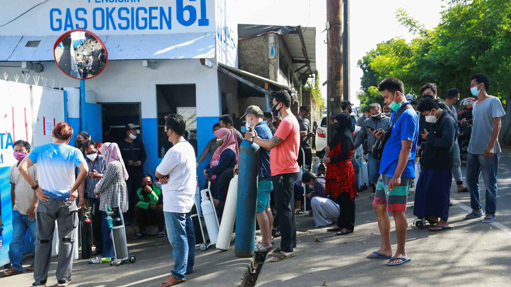 Un grupo de personas hace cola ante una fábrica en Yakarta para rellenar sus bombonas de oxígeno.