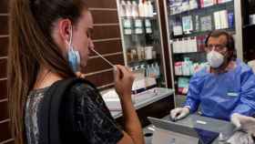 Una joven se hace un test de antígeno en una farmacia.